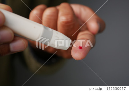 Close-Up Of Pricked Finger With Tiny Blood Drop For Diabetes Test  132330957