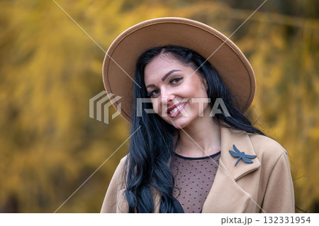Beautiful brunette girl in beige coat and hat posing in autumn park Beautiful brunette girl in beige coat and hat posing in autumn park 132331954
