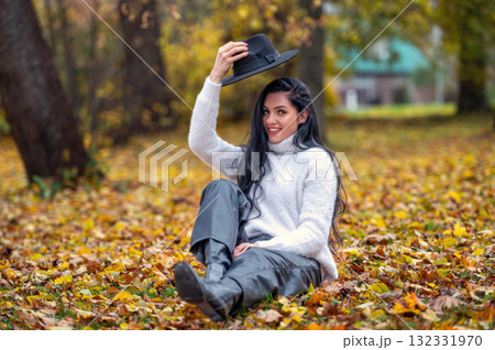 Young beautiful brunette woman in a white sweater and black hat in an autumn park 132331970