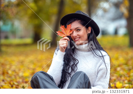 Portrait of a beautiful young woman in the autumn park with maple leaf Portrait of a beautiful young woman in the autumn park with maple leaf 132331971