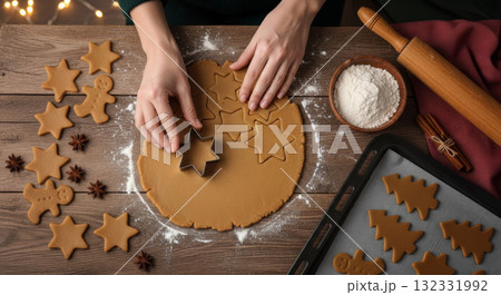 Hands cutting star and gingerbread man cookies from dough for Christmas baking on a wooden table. 132331992