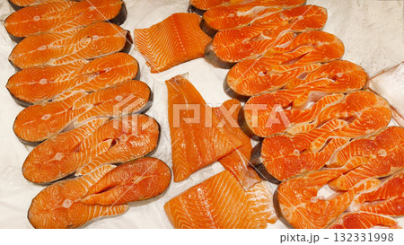 Fresh salmon fillets and steaks on ice in a fish market or supermarket display case. Healthy eating concept, seafood market, protein diet, and fresh fish. 132331998