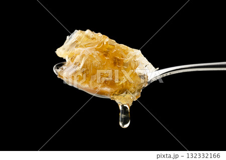 黒背景にスプーンですくい上げた巣みつから滴るはちみつ 132332166