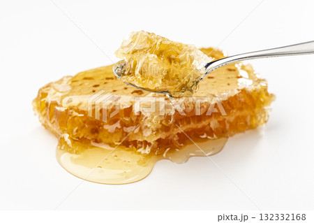白背景にスプーンですくい上げた巣みつから滴るはちみつ 132332168