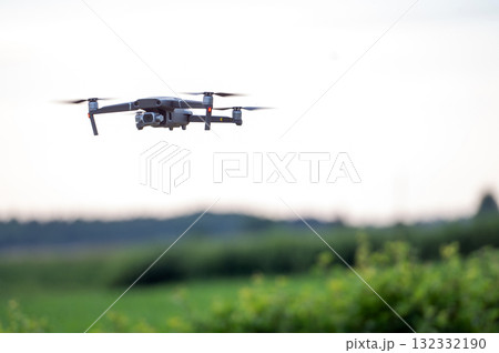 Drone flying in the sky over a green field with blurred background 132332190
