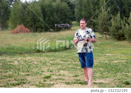 A man operating the drone by remote control on the meadow. 132332195