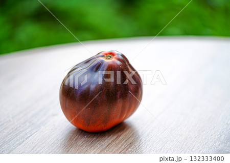 fresh picked multicolored striped and streaky black, purple, and red tomatoes on a wooden table fresh picked multicolored striped and streaky black, purple, and red tomatoes on a wooden table 132333400