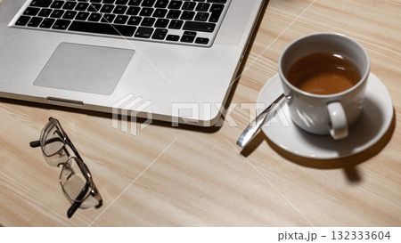 Desk with laptop, eyeglasses and a cup of tea on a wooden table - image Desk with laptop, eyeglasses and a cup of tea on a wooden table - image 132333604