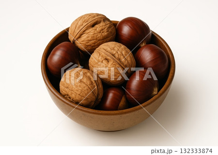 bowl filled with whole walnuts and chestnuts on white background, perfect for autumn or fall themed projects. 132333874