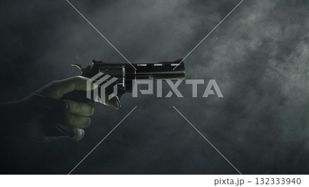 Witch hand with a long black nail holding a handgun with a dark background. Zombie, devil, evil, satan, or monster hand. Concept of Spooky Halloween 132333940