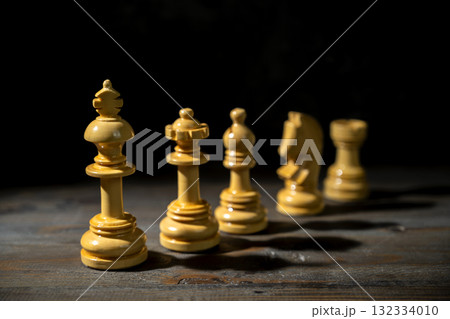 Closeup view of the white chess king standing with other chess pieces against a dark background. Concept of leadership or management 132334010