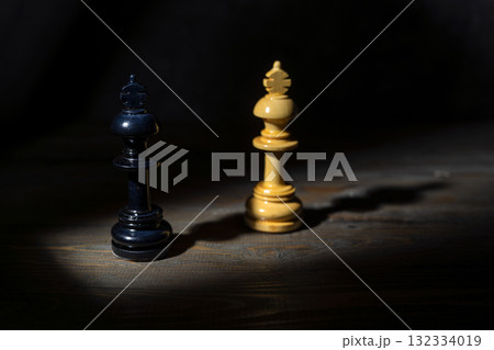Closeup view of a black and white chess king standing against a dark background. Concept of leadership 132334019