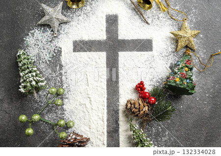 Christian cross formed by a dusting of white powder with various colorful Christmas ornaments on the table. Concept of faith, holiday celebration, and spiritual reflection Christian cross formed by a dusting of white powder with various colorful Christmas ornaments on the table. Concept of faith, holiday celebration, and spiritual reflection 132334028
