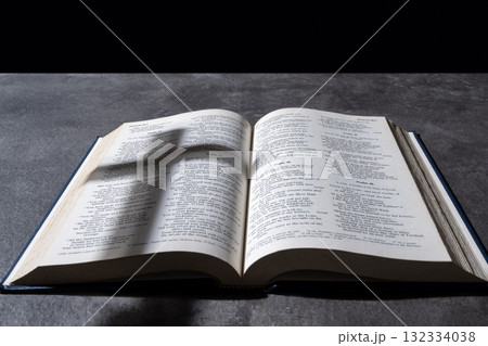 Blue book of Holy bible and silhouette of a Christian cross. Standing on table with a dark background. Symbol of faith in God. Concept of Spirituality, Christianity, religion, faith, Jesus, or belief Blue book of Holy bible and silhouette of a Christian cross. Standing on table with a dark background. Symbol of faith in God. Concept of Spirituality, Christianity, religion, faith, Jesus, or belief 132334038