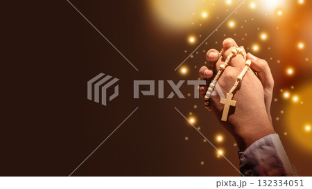 Prayer holding rosary beads with a Christian cross with glitter lights and blurred bokeh lights background. Concept of Christianity, religious, faith, Jesus, or belief Prayer holding rosary beads with a Christian cross with glitter lights and blurred bokeh lights background. Concept of Christianity, religious, faith, Jesus, or belief 132334051