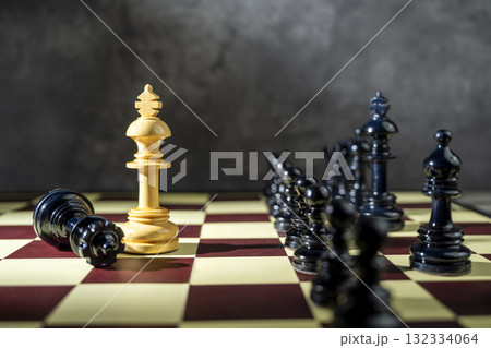 Closeup view of a white chess king standing against the opposing pieces on the chessboard. Concept of strategy 132334064