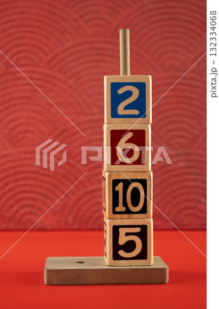Stack of wooden number blocks with various numbers on a red background 132334068