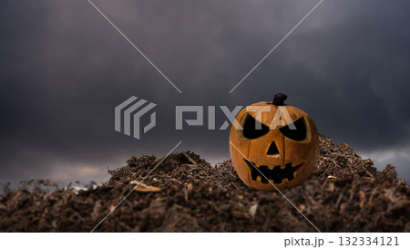 Closeup view of a Jack o' Lantern on the ground with dark and dramatic cloudscape background. The scene is scary and mysterious. Concept of Spooky Halloween Closeup view of a Jack o' Lantern on the ground with dark and dramatic cloudscape background. The scene is scary and mysterious. Concept of Spooky Halloween 132334121