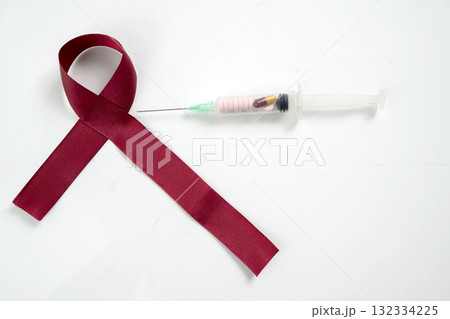 Red ribbon and syringe on a white background. Symbolizing awareness and support for HIV or AIDS patients. World Aids Day. Concept of Healthcare and Medicine 132334225