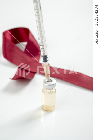 Red ribbon and syringe with vial on a white background. Symbolizing awareness and support for HIV or AIDS patients. World Aids Day. Concept of Healthcare and Medicine Red ribbon and syringe with vial on a white background. Symbolizing awareness and support for HIV or AIDS patients. World Aids Day. Concept of Healthcare and Medicine 132334234