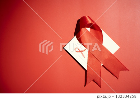 Red ribbon on a red background. Symbolizing awareness and support for HIV or AIDS patients. World Aids Day. Concept of Healthcare and Medicine Red ribbon on a red background. Symbolizing awareness and support for HIV or AIDS patients. World Aids Day. Concept of Healthcare and Medicine 132334259