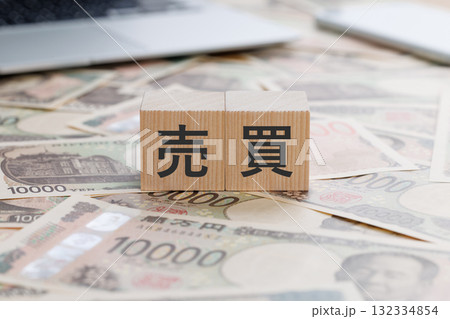 お金の上に売買と書かれたブロック 132334854