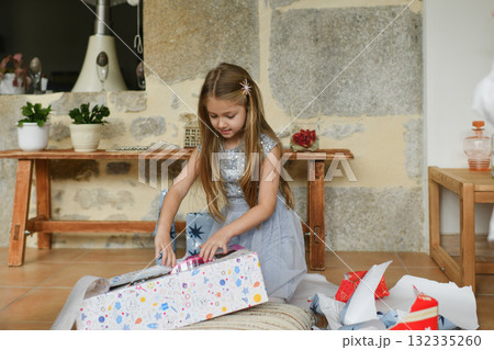 A girl unwraps the christmas presents 132335260