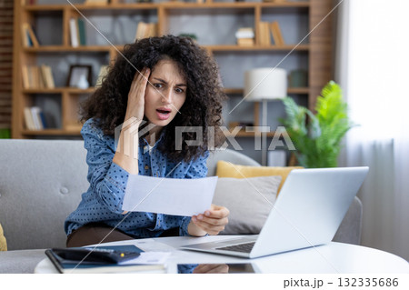 Woman feeling shocked and overwhelmed by an unexpected bill while checking finances on a laptop at home, experiencing financial stress and budget difficulties 132335686