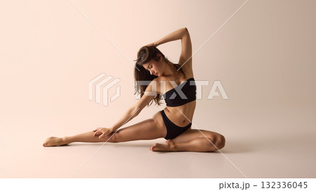 Woman in black lingerie stretching gracefully on floor symbolizing balance and body awareness Woman in black lingerie stretching gracefully on floor symbolizing balance and body awareness 132336045