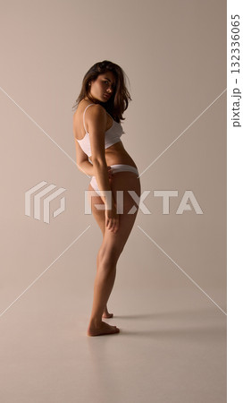 Elegant woman in minimal underwear turning back with confident natural posture 132336065