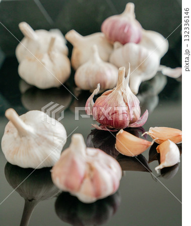 Natural garlic bulbs and cloves on dark mirror surface with soft reflection. Fresh organic spice concept 132336146
