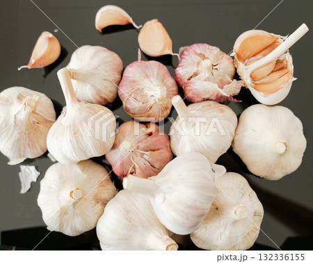 Group of garlic heads and loose cloves on dark background with natural light rustic kitchen composition 132336155
