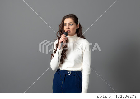 attractive female conference speaker during presentation, holds microphone and makes some gestures 132336278