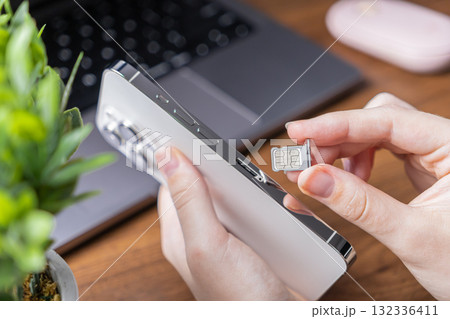 Person's hand holds a sleek smartphone, preparing to insert a nano SIM card, representing essential mobile network setup and modern telecommunications technology 132336411