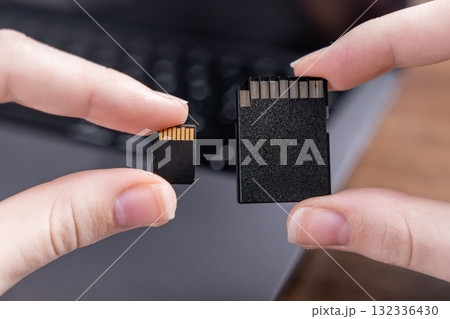 Human hands holding micro SD and standard SD cards, comparing their distinct sizes for diverse digital data storage across electronic devices Human hands holding micro SD and standard SD cards, comparing their distinct sizes for diverse digital data storage across electronic devices 132336430