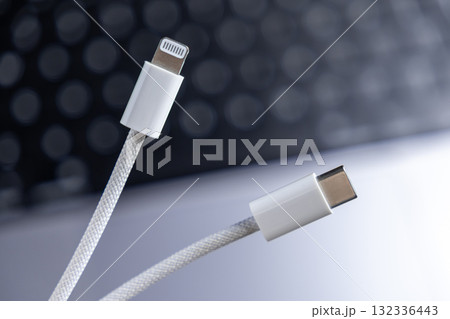 Modern white braided cables displaying Lightning and USB-C connectors, highlighting universal connectivity and compatibility for rapid device charging and efficient data transfer 132336443