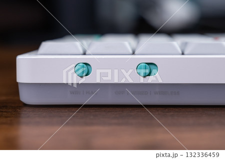 Stylish mechanical keyboard side with vibrant teal toggle switches managing WIN MAC operating system and WIRED WIRELESS connectivity for ultimate computer versatility Stylish mechanical keyboard side with vibrant teal toggle switches managing WIN MAC operating system and WIRED WIRELESS connectivity for ultimate computer versatility 132336459