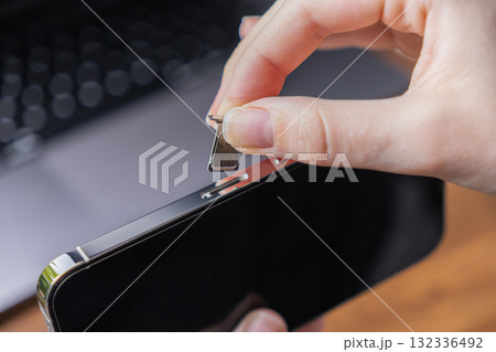 Human hand carefully inserting a dual SIM card tray with microchip into a sleek smartphone for seamless mobile network connectivity and digital communication 132336492