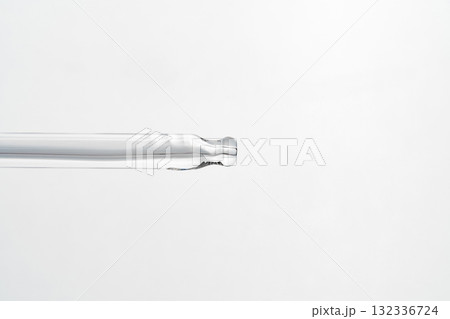 Close-up of a pipette or glass dropper on a backlit white background. Concept of cosmetic, skincare, serum, product detail, minimalism, transparency, beauty photography. Close-up of a pipette or glass dropper on a backlit white background. Concept of cosmetic, skincare, serum, product detail, minimalism, transparency, beauty photography. 132336724