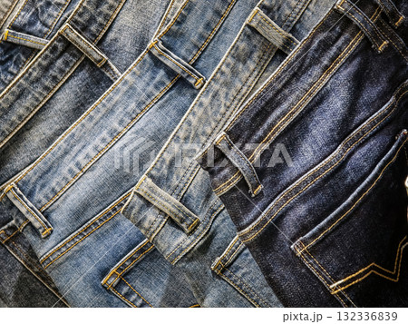 Various styles of denim jeans displayed horizontally showcasing different shades and textures in a clothing store setting Various styles of denim jeans displayed horizontally showcasing different shades and textures in a clothing store setting 132336839