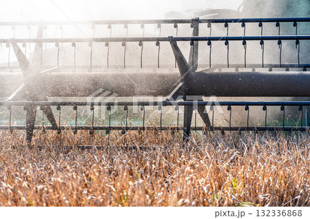 the reel of a agricultural combine harvester cuts wheat cereals in the dust, harvesting season 132336868
