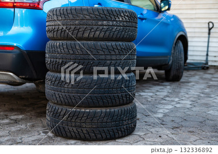 a set of winter tires next to the car in the wheel service, the concept of seasonal tire change a set of winter tires next to the car in the wheel service, the concept of seasonal tire change 132336892