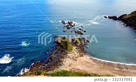 Rocky tombolo and sea stacks on a tranquil blue coastline 132337091