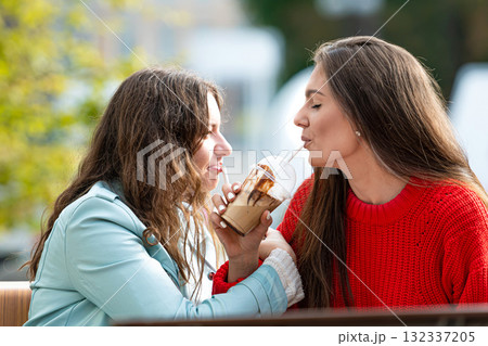 two milenial girlfriend spend free time in outdoor cafe with cocktails, laughing and talking two milenial girlfriend spend free time in outdoor cafe with cocktails, laughing and talking 132337205