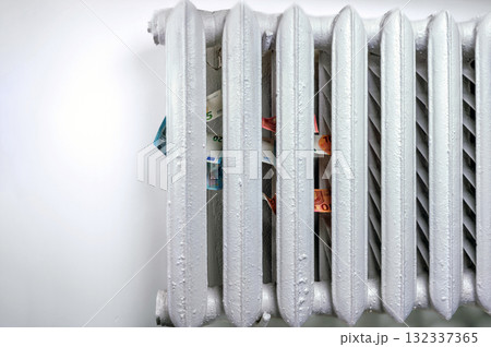 euro banknotes in a central heating radiator, the concept of expensive heating costs, closeup 132337365