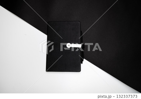 black organizer or notebook with pen on two-color black and white background, mockup, copy space 132337373