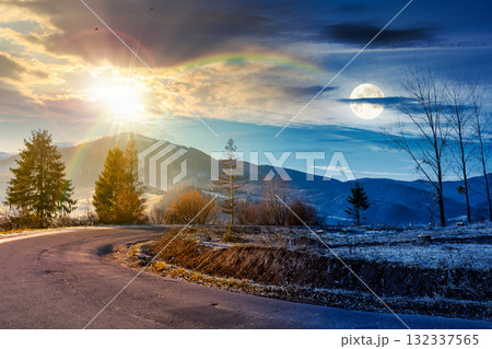 country road in mountains. day and night time change concept. beautiful countryside landscape in late autumn. fir trees on the roadside with sun and moon. scenic view of distant ridge in snow country road in mountains. day and night time change concept. beautiful countryside landscape in late autumn. fir trees on the roadside with sun and moon. scenic view of distant ridge in snow 132337565