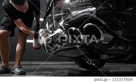 Worker washing car exhaust with foam sponge during detailing procedure 132337684