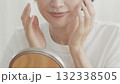 室内で鏡をみながら肌の調子を確認するミドル女性 132338505