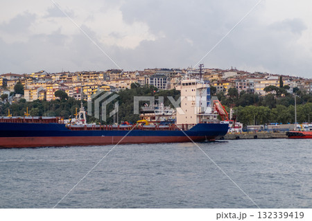 Vessel navigating the Bosphorus Strait with hillside cityscape in the background at dusk 132339419